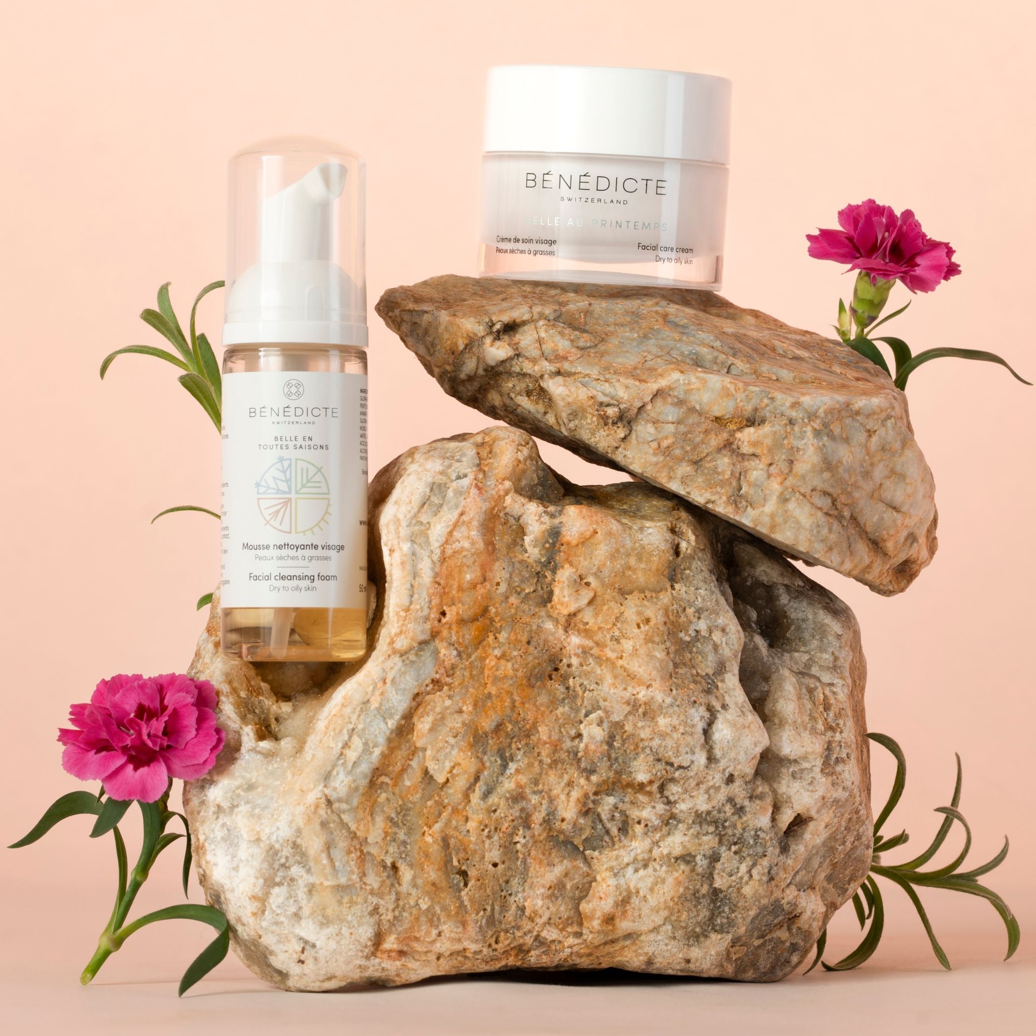 Visuel de la crème Belle au Printemps et de la mousse nettoyante photographiés sur de la roche avec des branches de fleurs sur fond rosé