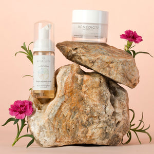 Visuel de la crème Belle au Printemps et de la mousse nettoyante photographiés sur de la roche avec des branches de fleurs sur fond rosé