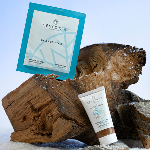 Visuel du gommage et du masque hiver photographiés sur une buche de bois sur un fond bleu
