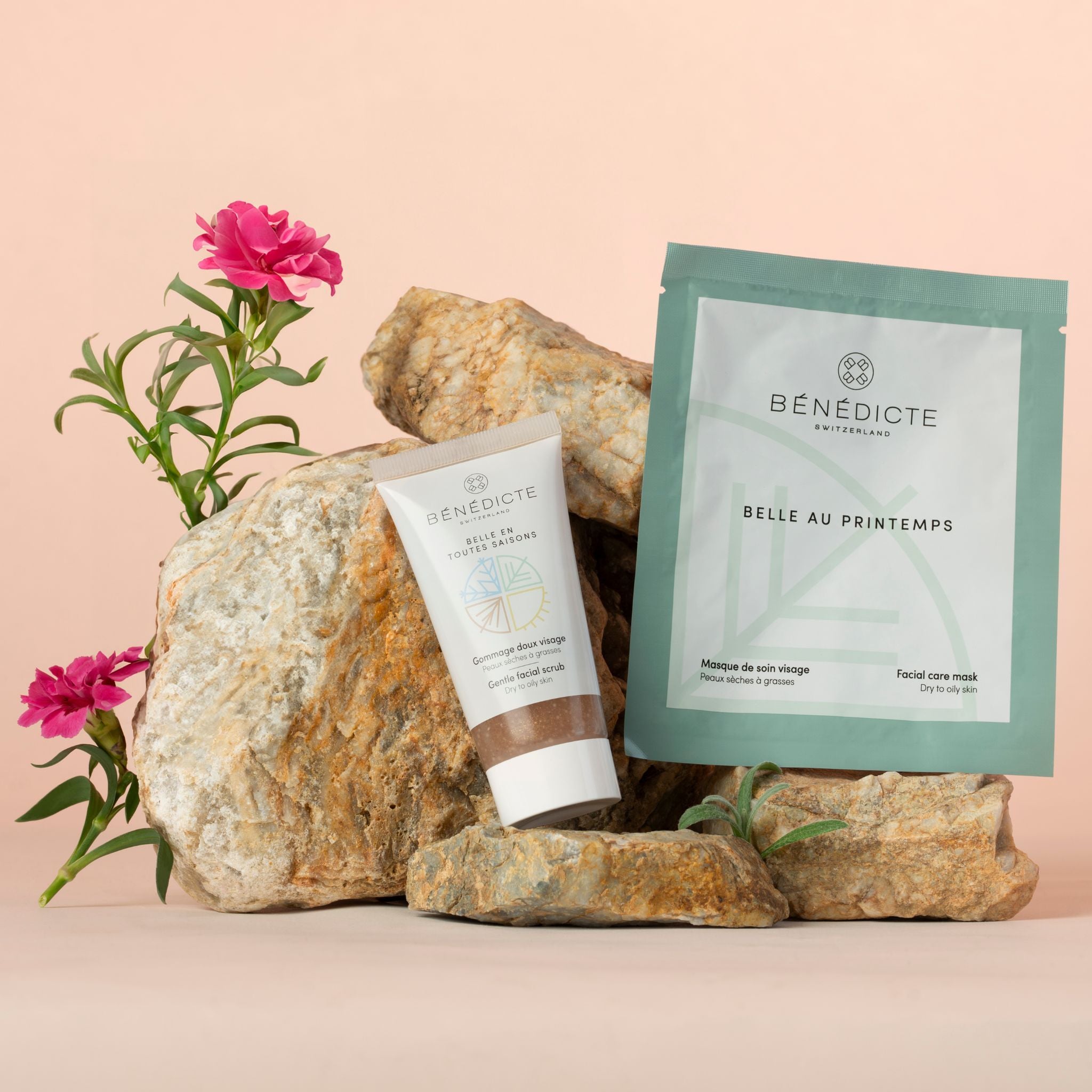 Visuel du gommage et du masque Printemps photographiés sur de la roche avec des branches de fleurs sur fond rosé