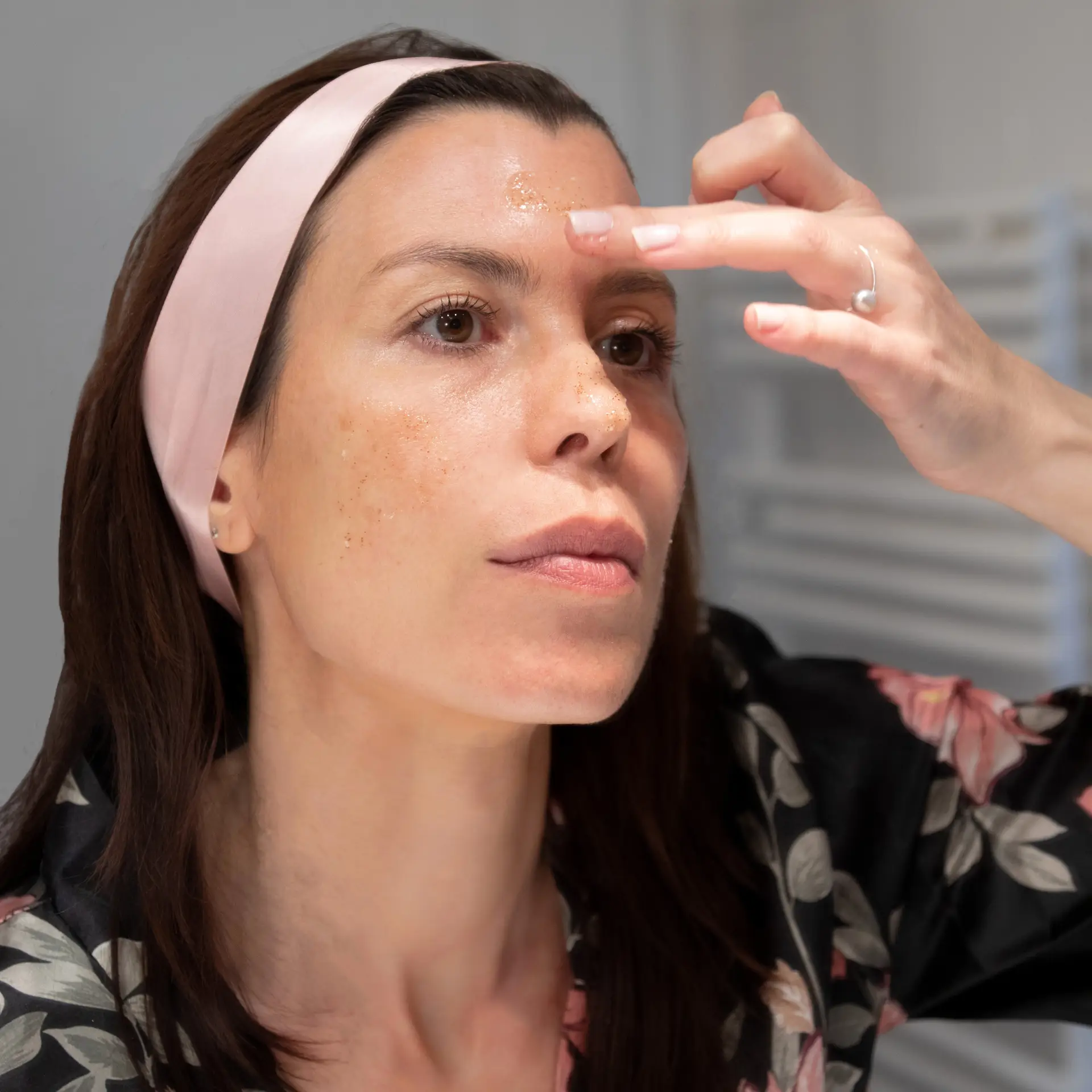 Valérie devant un miroir en train de s'étaler le gommage Bénédicte sur le visage